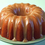 A moist banana pound cake drizzled with rich caramel glaze, served on a white plate, perfect for dessert or special occasions.